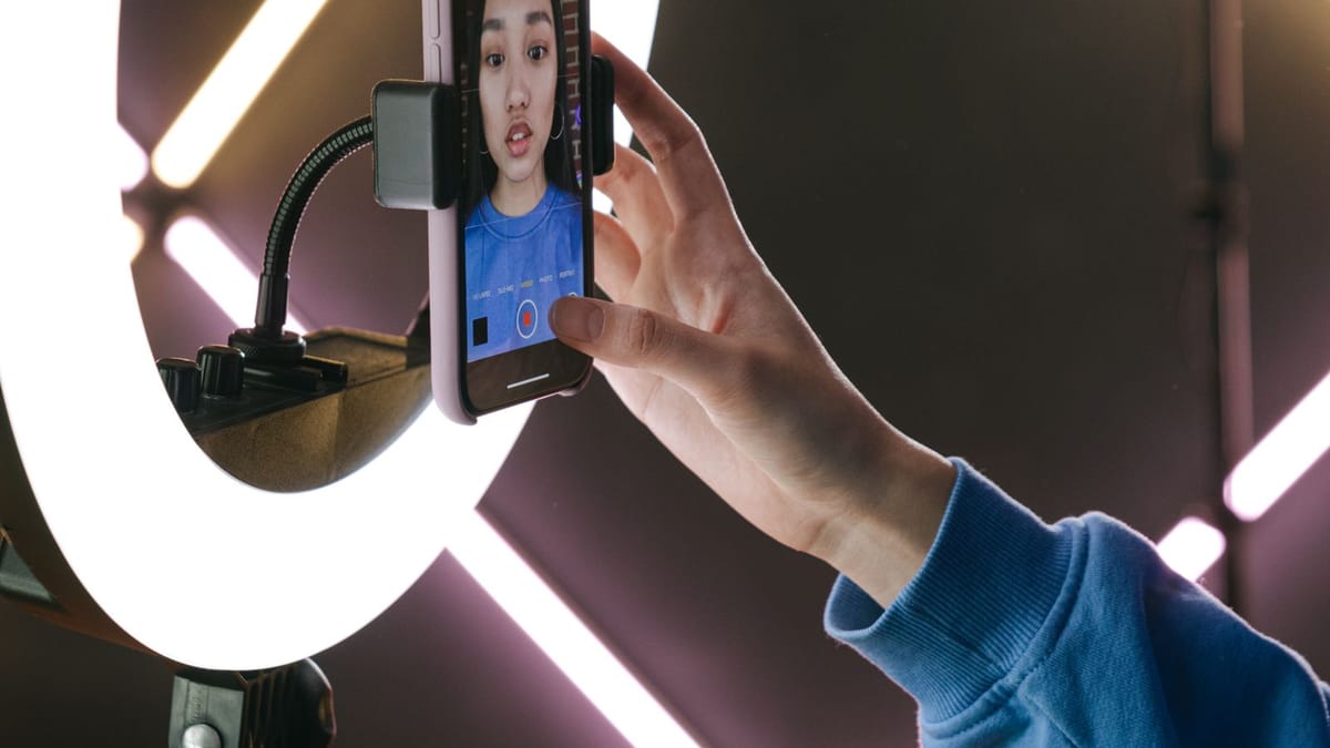 Young woman filming herself on a phone with a ring light