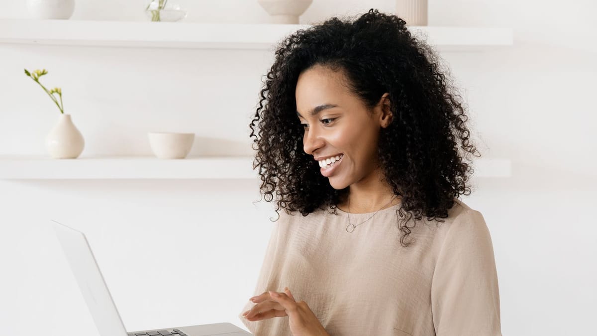 Confident young woman smiling while working on a laptop at home