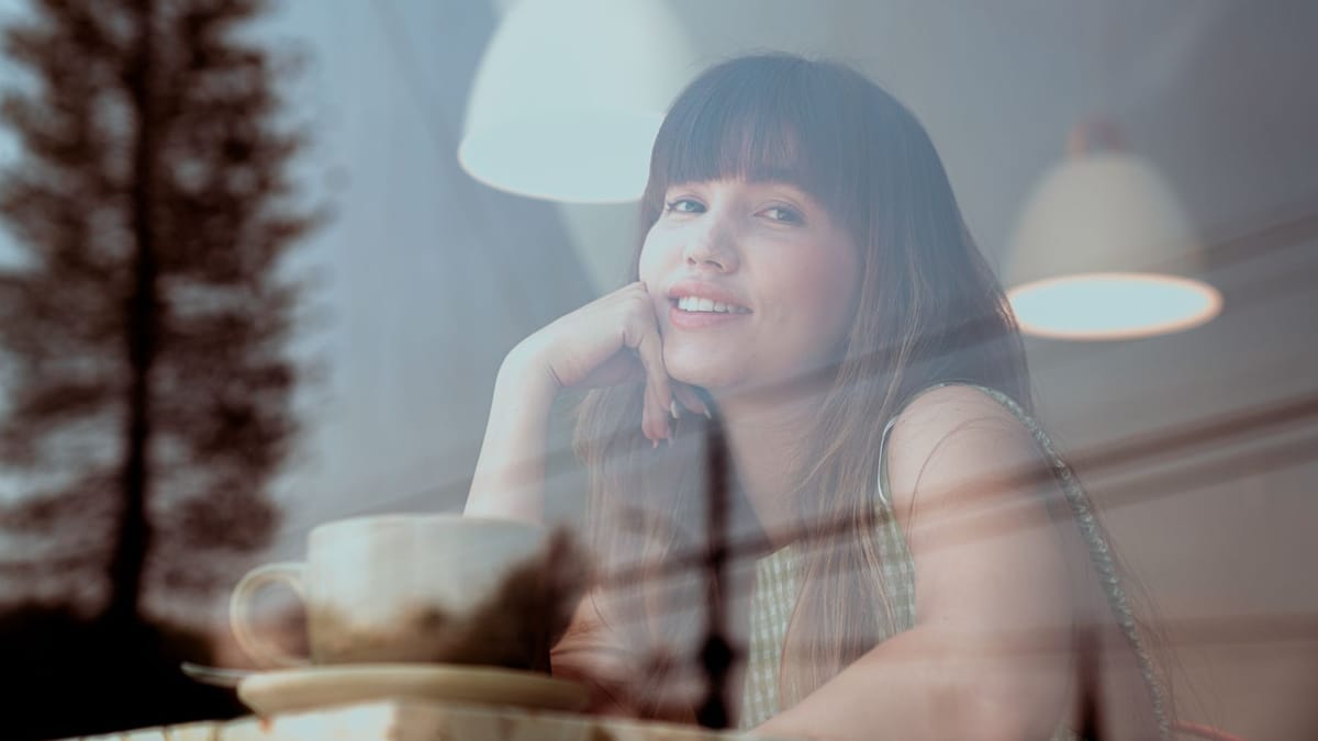 Young woman relaxing with a coffee by a café window